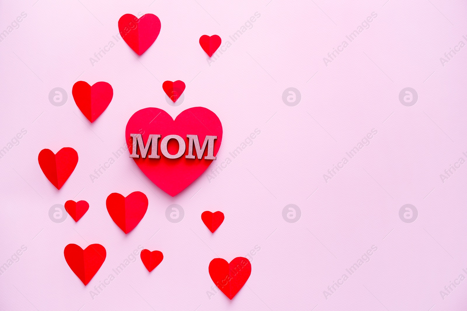 Photo of Beautiful composition with word MOM and paper hearts on color background. Happy Mother's Day