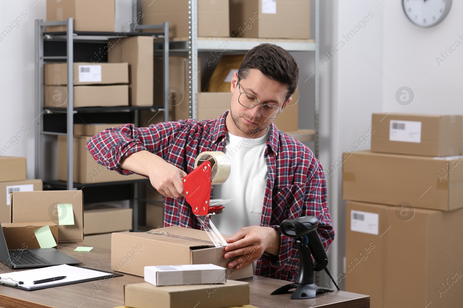 Photo of Seller taping parcel at workplace in office. Online store