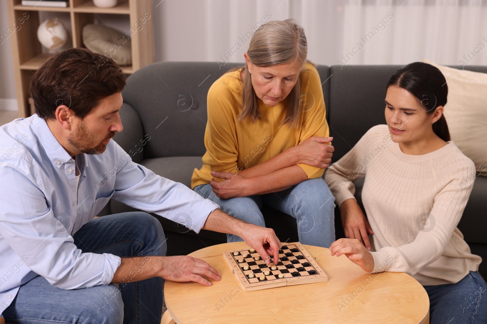 Photo of Family playing checkers at coffee table in room