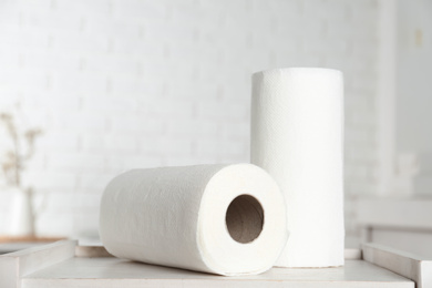 Photo of Rolls of paper towels on white wooden table in kitchen
