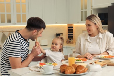 Happy family having breakfast together at table in kitchen