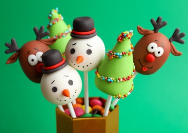 Photo of Delicious Christmas themed cake pops on green background, closeup