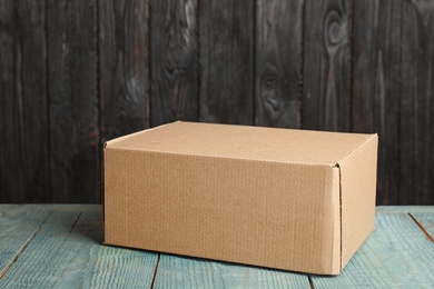 Cardboard box on light blue wooden table against dark background