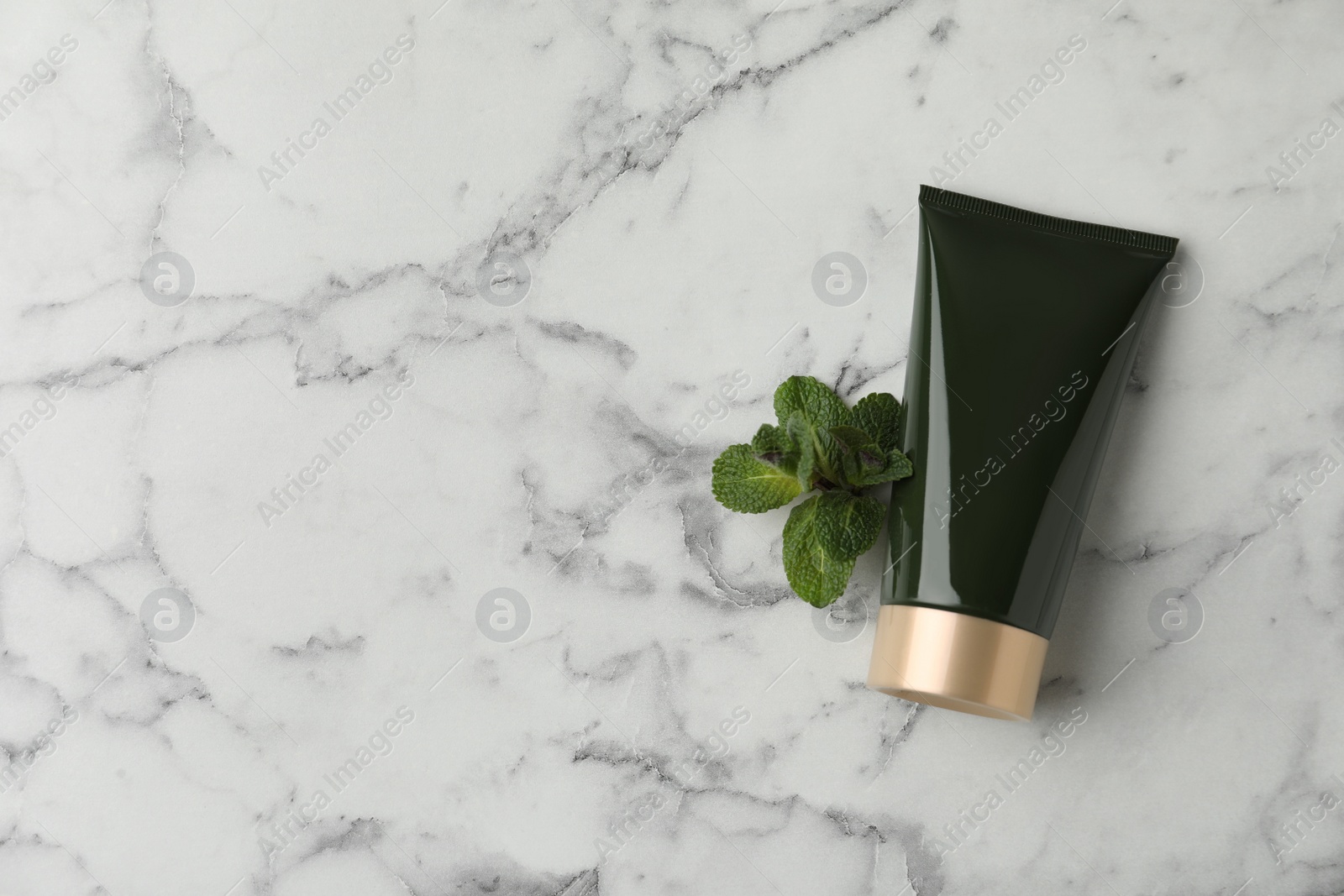 Photo of Cosmetic product and mint on white marble table, flat lay. Space for text