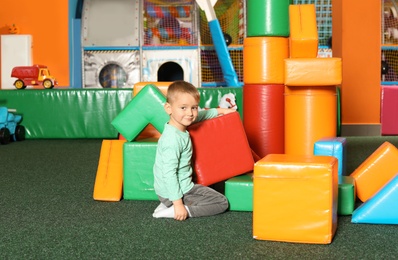 Cute child playing with colorful building blocks indoors