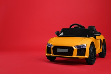 Child's electric toy car on red background. Space for text