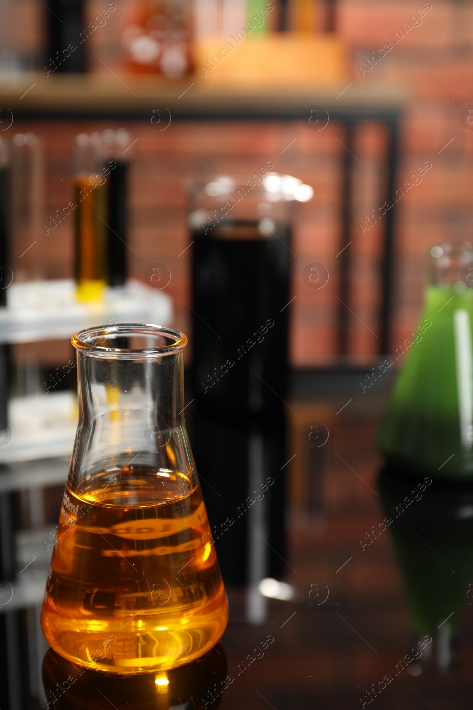 Photo of Laboratory glassware with different types of oil on black mirror table, closeup