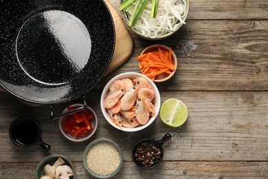 Photo of Flat lay composition with black wok, spices and products on wooden table. Space for text