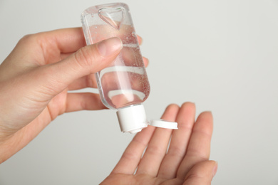 Photo of Woman applying antiseptic gel on light grey background, closeup