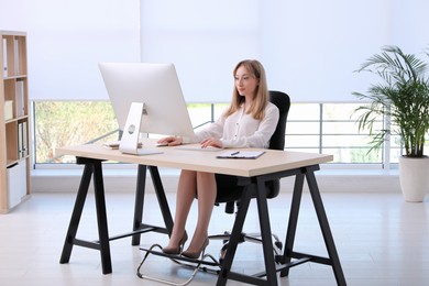 Woman using footrest while working on computer in office