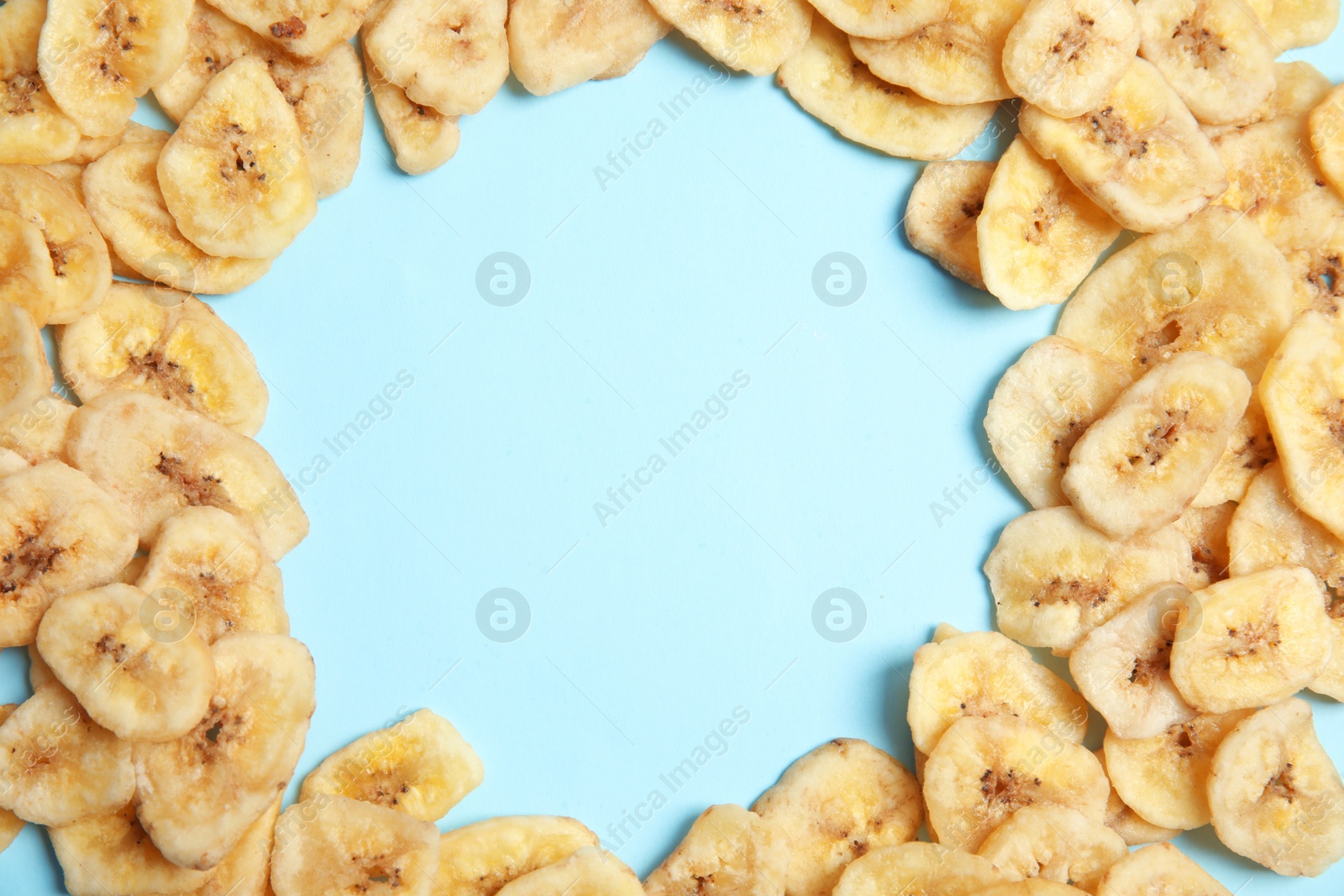 Photo of Frame made of sweet banana slices on color background, top view with space for text. Dried fruit as healthy snack