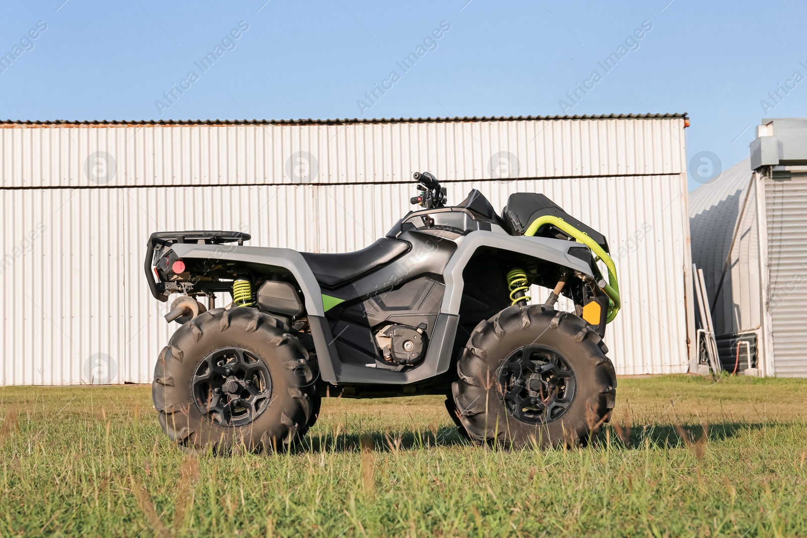 Photo of Modern quad bike in field near hangars on sunny day