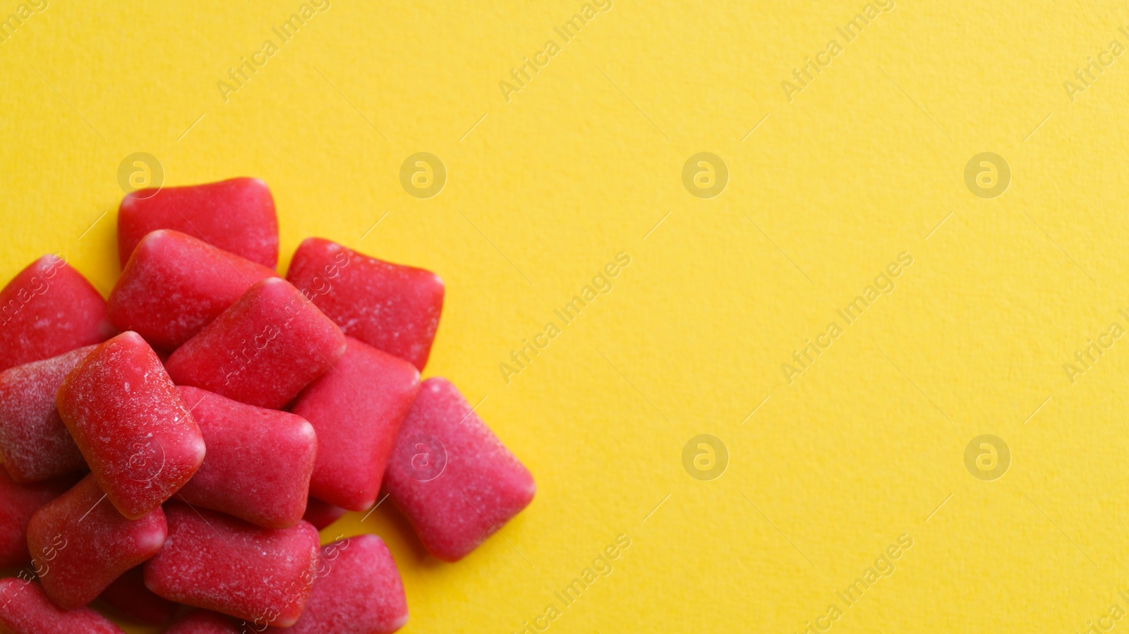 Photo of Sweet chewing gums on yellow background, flat lay. Space for text