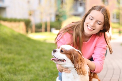 Young woman with adorable Cavalier King Charles Spaniel dog outdoors