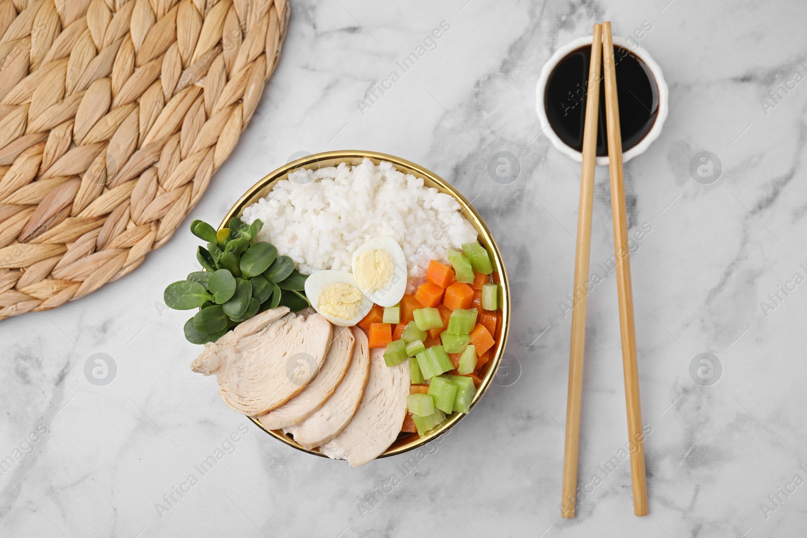 Photo of Delicious poke bowl of meat, egg, rice and vegetables served with soy sauce on white marble table, flat lay