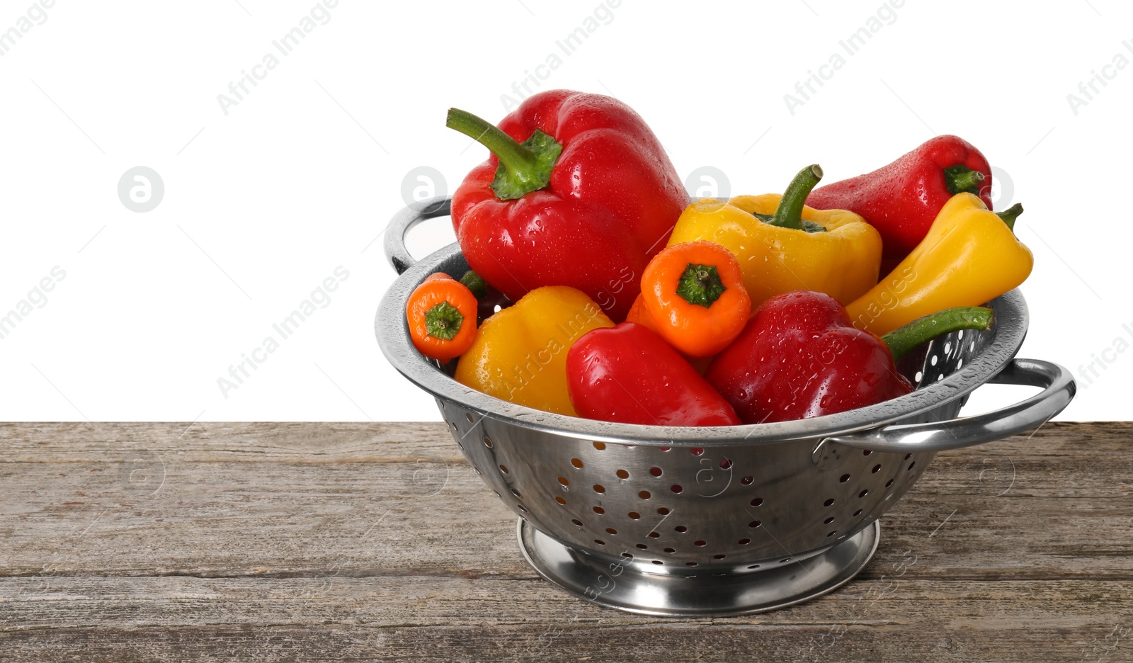 Photo of Metal colander with fresh peppers on wooden table against white background, space for text