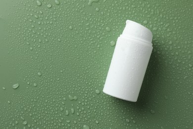 Moisturizing cream in bottle on green background with water drops, top view. Space for text