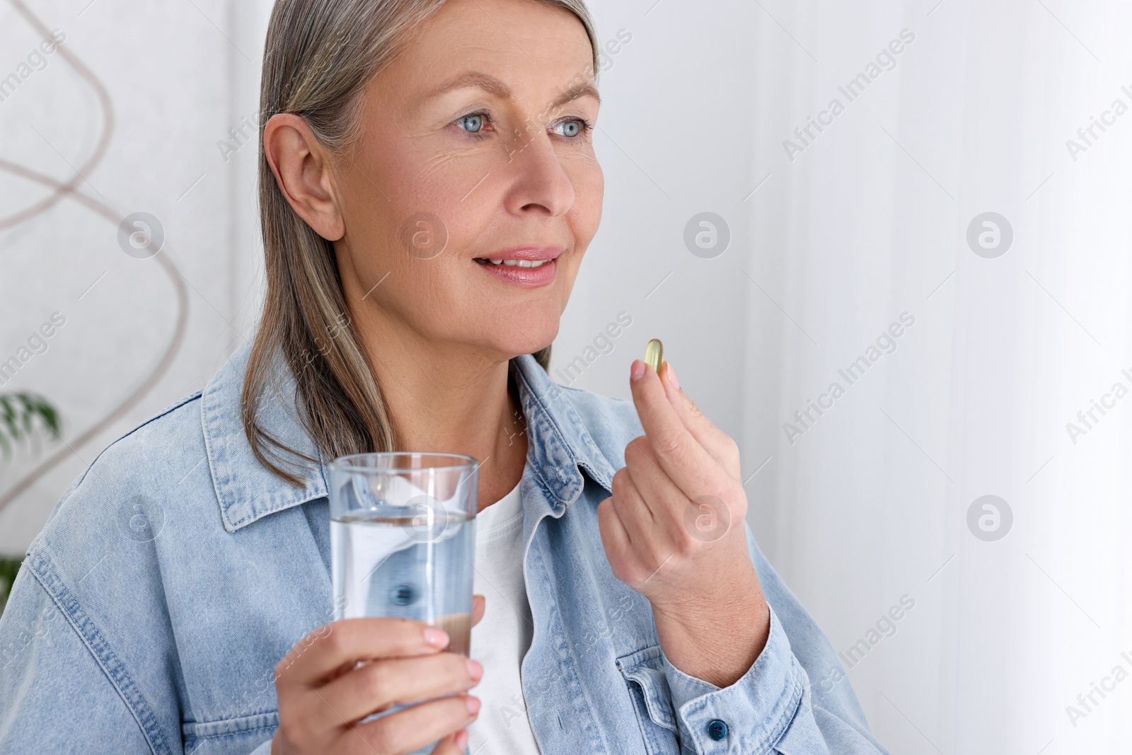 Photo of Beautiful woman taking vitamin pill at home