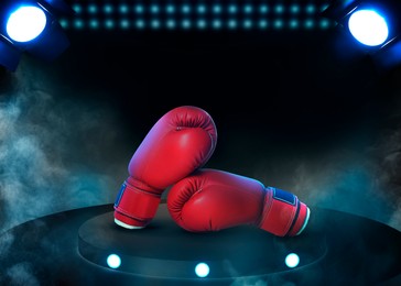 Pair of boxing gloves on black stand illuminated by spotlights