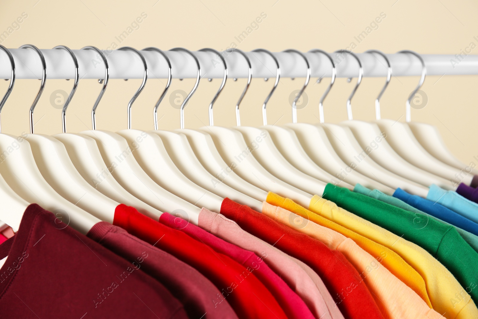 Photo of Many t-shirts hanging in order of rainbow colors, closeup