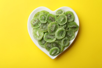 Photo of Plate with slices of kiwi on color background, top view. Dried fruit as healthy food