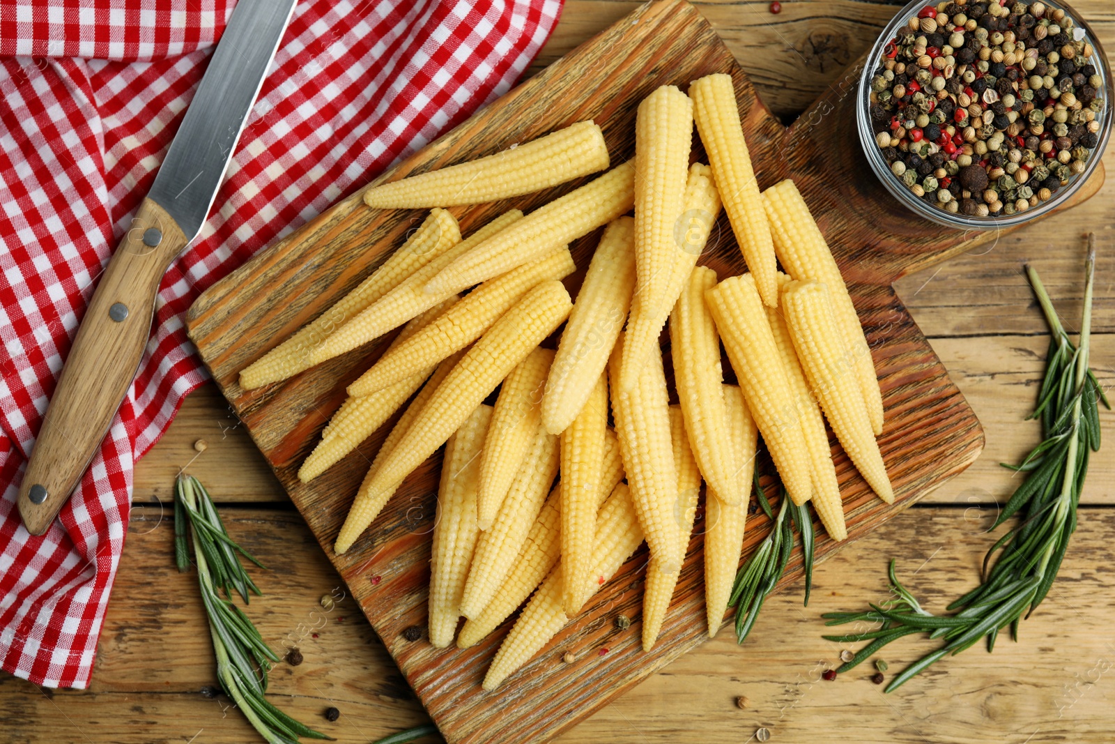 Photo of Fresh baby corn cobs and spices on wooden table, flat lay