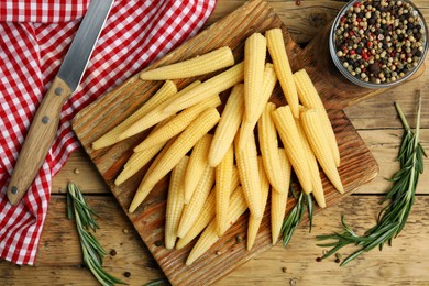 Fresh baby corn cobs and spices on wooden table, flat lay