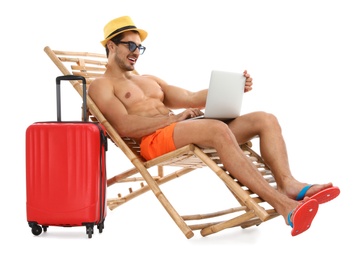 Photo of Young man with laptop and suitcase on sun lounger against white background. Beach accessories