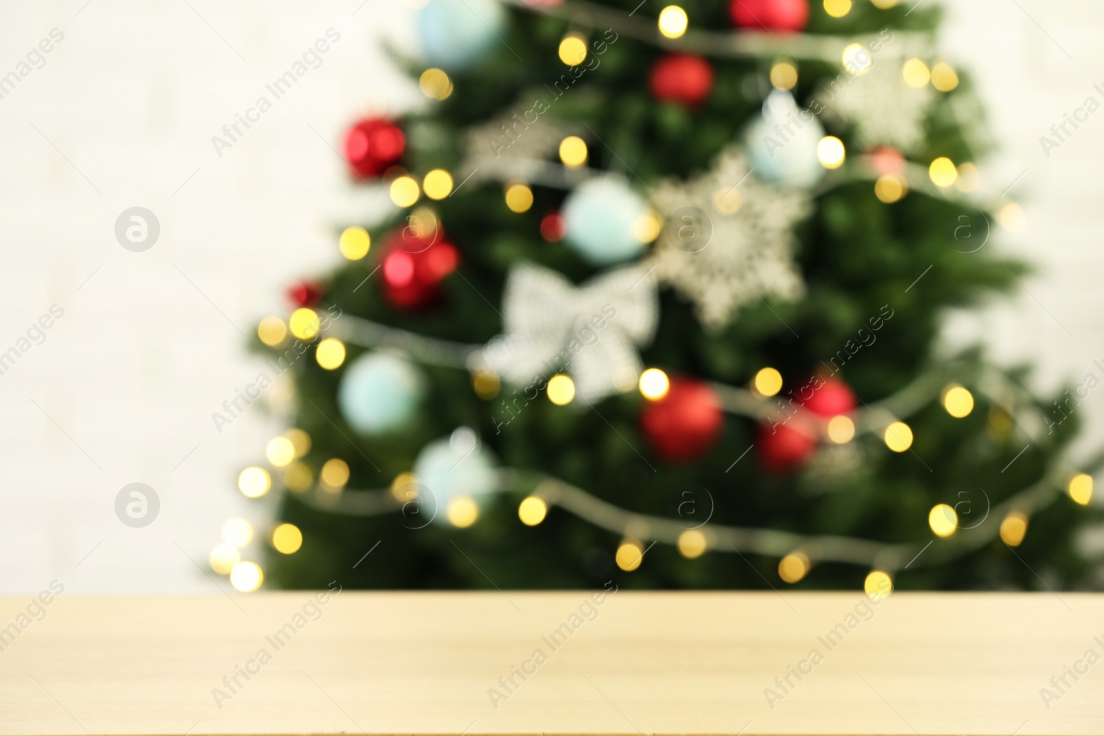 Photo of Empty wooden table against fir tree with Christmas lights, blurred view. Space for design