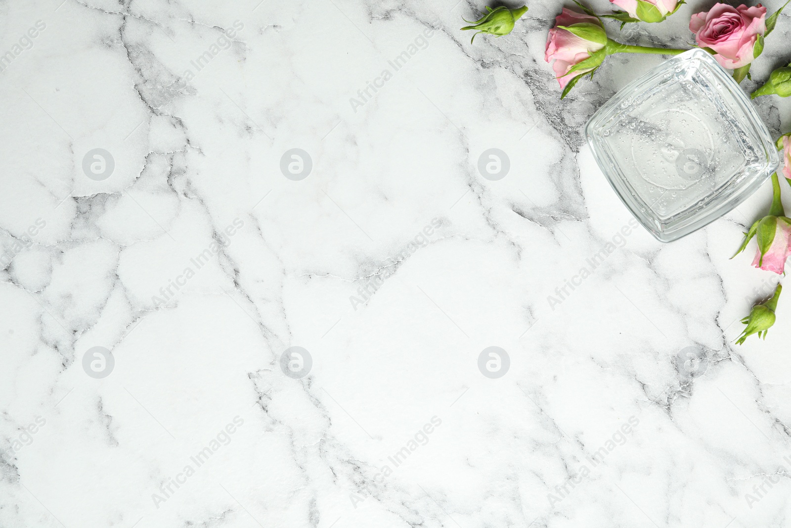 Photo of Flat lay composition with cosmetic gel and beautiful flowers on white marble table. Space for text