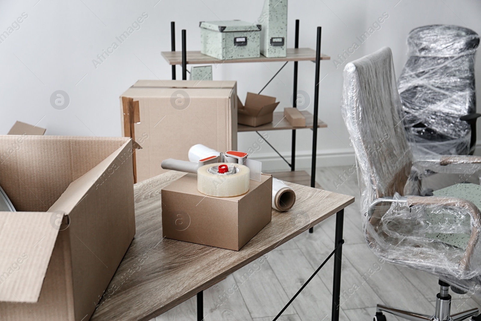 Photo of Carton boxes with stuff on table in room. Office move concept