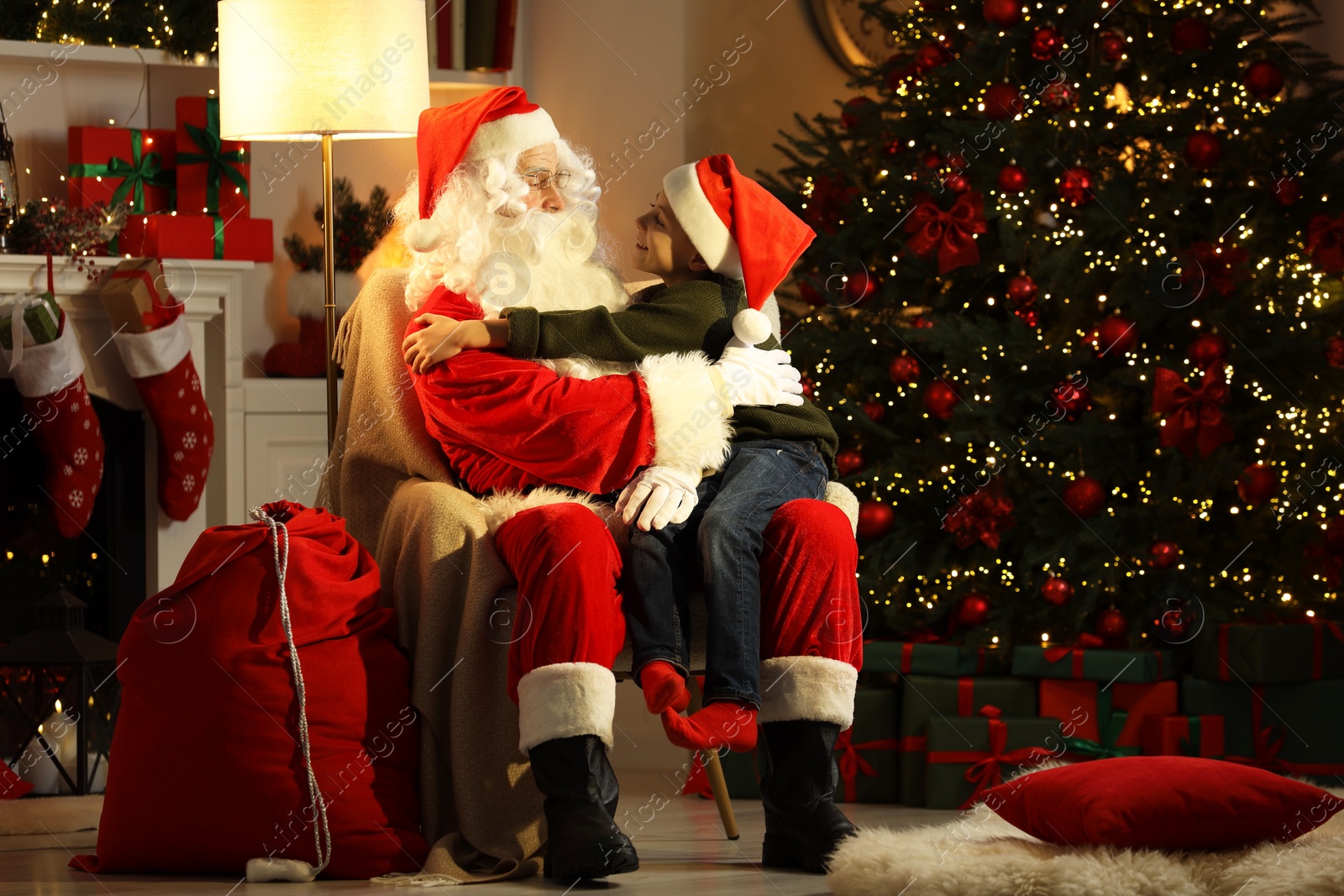 Photo of Merry Christmas. Little boy sitting on Santa's knee at home