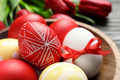 Bowl with painted Easter eggs on table, closeup