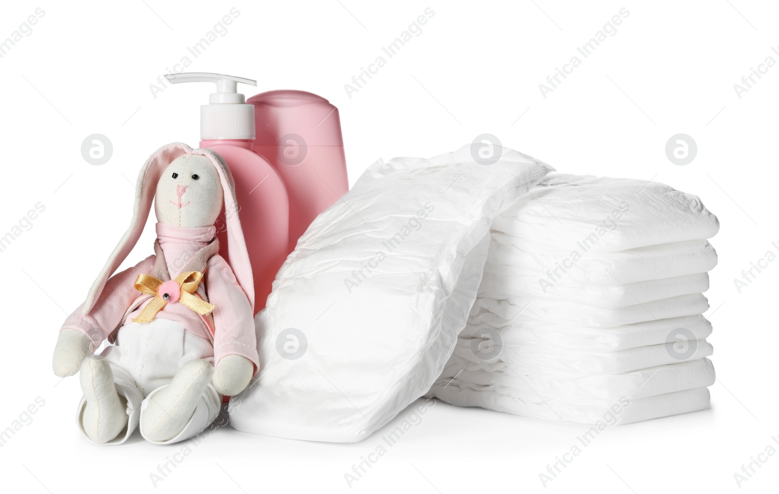 Photo of Stack of disposable diapers, toy bunny and toiletries on white background