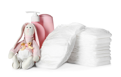 Photo of Stack of disposable diapers, toy bunny and toiletries on white background
