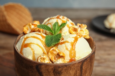 Photo of Delicious ice cream with caramel popcorn and sauce served on table, closeup