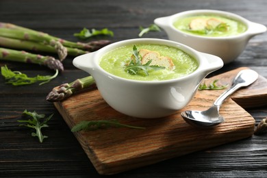 Delicious asparagus soup served on black wooden table