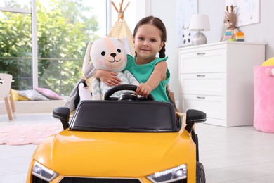 Adorable child with toy driving car in room at home