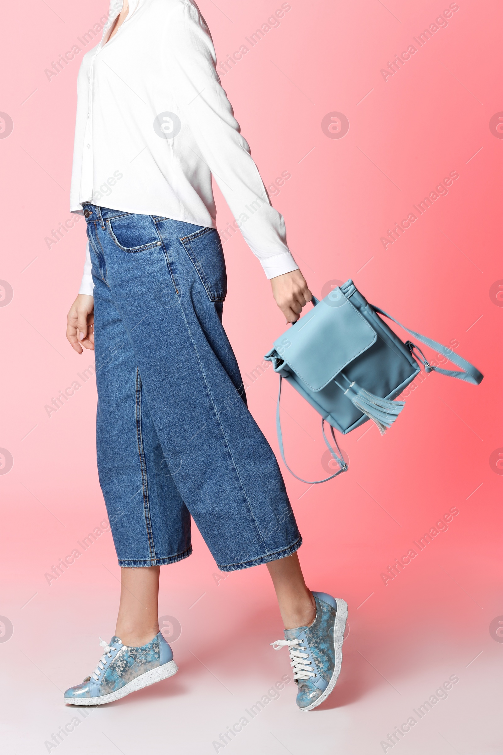 Photo of Woman in stylish shoes with backpack on color background