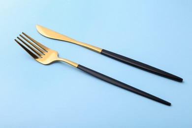 Stylish cutlery. Golden knife and fork on light blue background