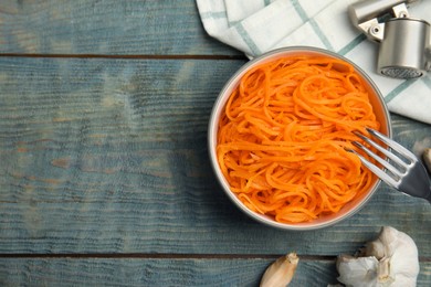Photo of Delicious Korean carrot salad and garlic on blue wooden table, flat lay. Space for text