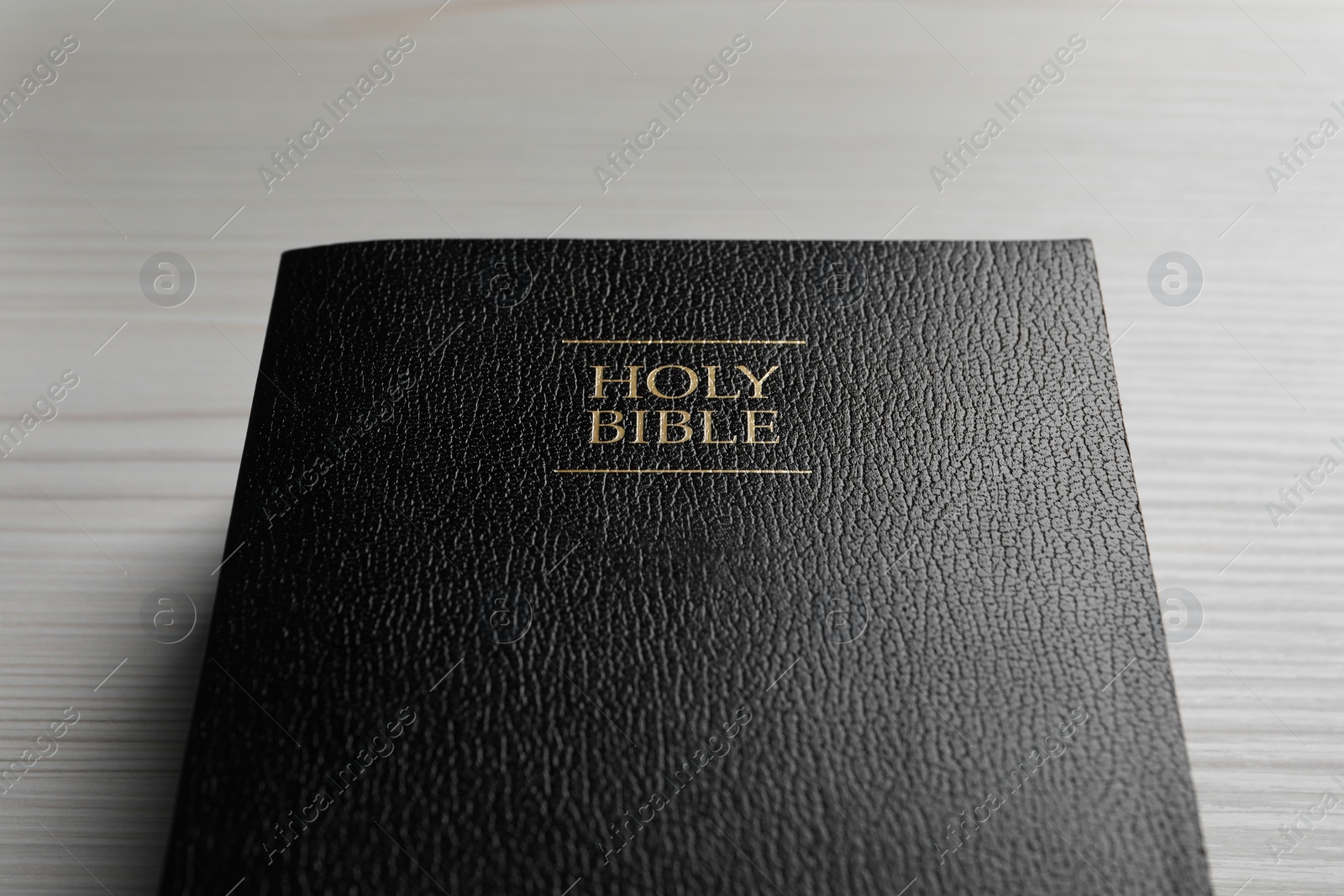 Photo of Holy Bible on white wooden table, closeup