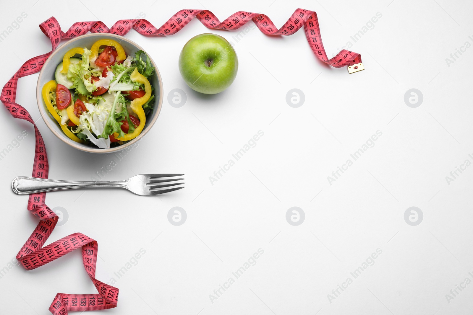 Photo of Measuring tape, salad, apple and fork on white background, flat lay. Space for text
