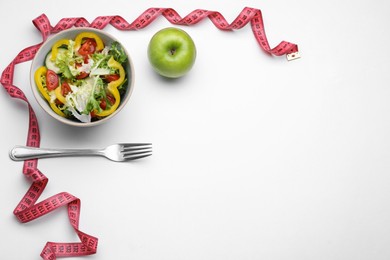 Photo of Measuring tape, salad, apple and fork on white background, flat lay. Space for text