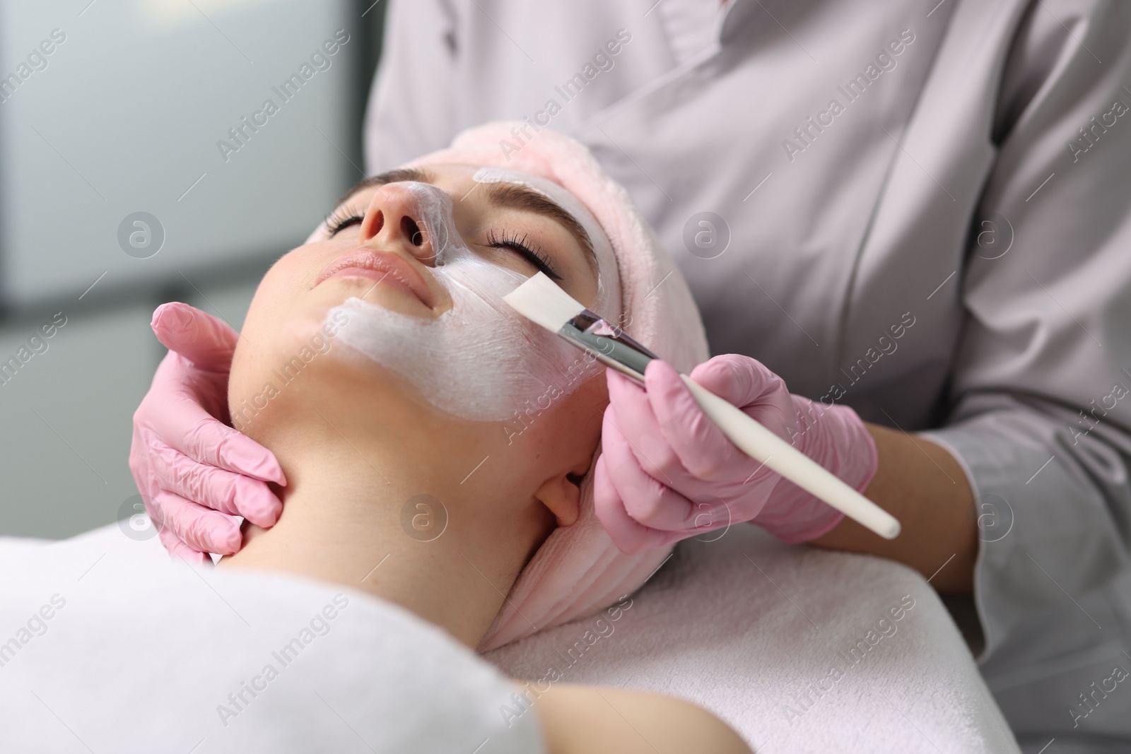 Photo of Cosmetologist applying mask on woman's face, closeup