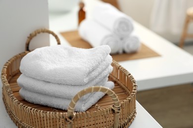 Photo of Stacked soft towels on white table in bathroom. Space for text