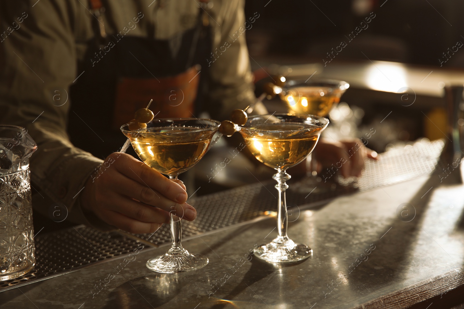 Photo of Barman with glasses of martini cocktail at counter, closeup. Space for text