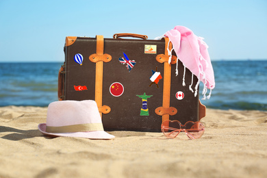 Image of Retro suitcase with travel stickers on beach