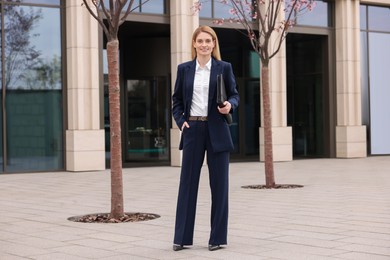 Photo of Female real estate agent with leather portfolio outdoors