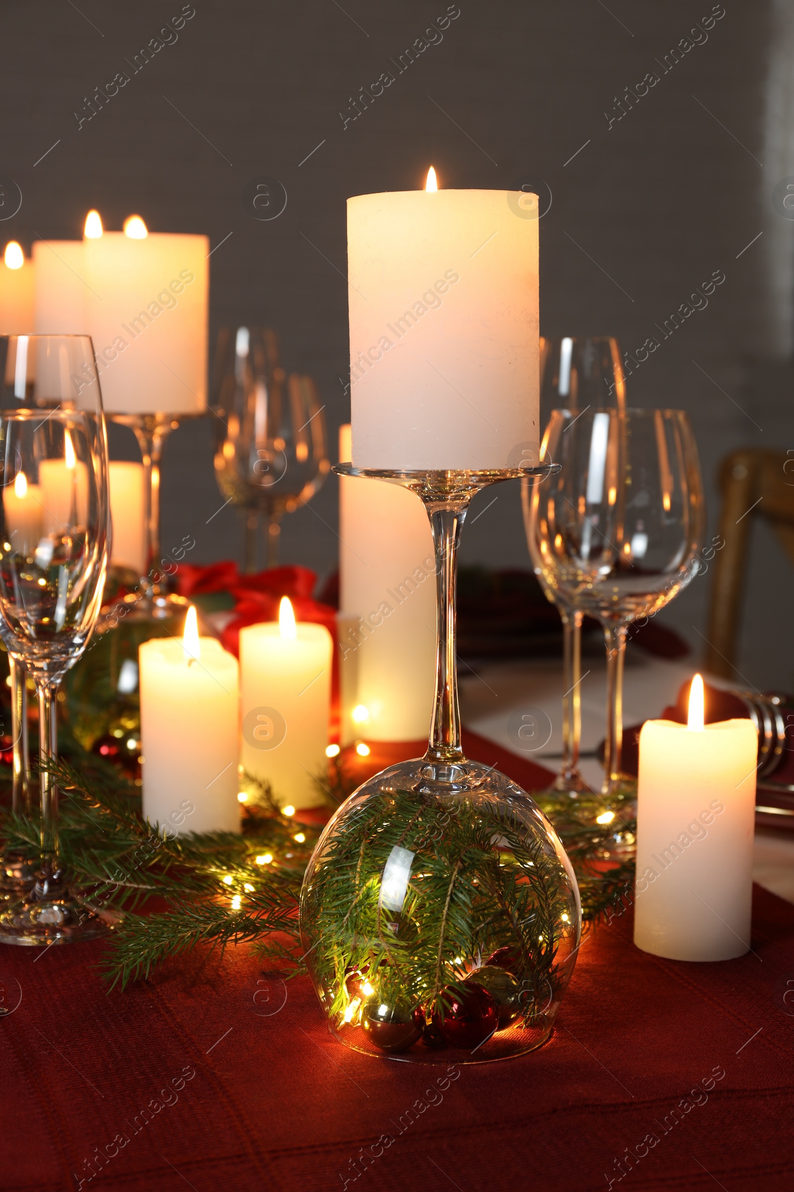 Photo of Christmas celebration. Burning candles, glasses and festive decor on table